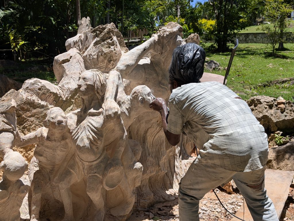 Sculptor Fitzroy Russell working on a massive stone sculpture at Jamaica Giants”