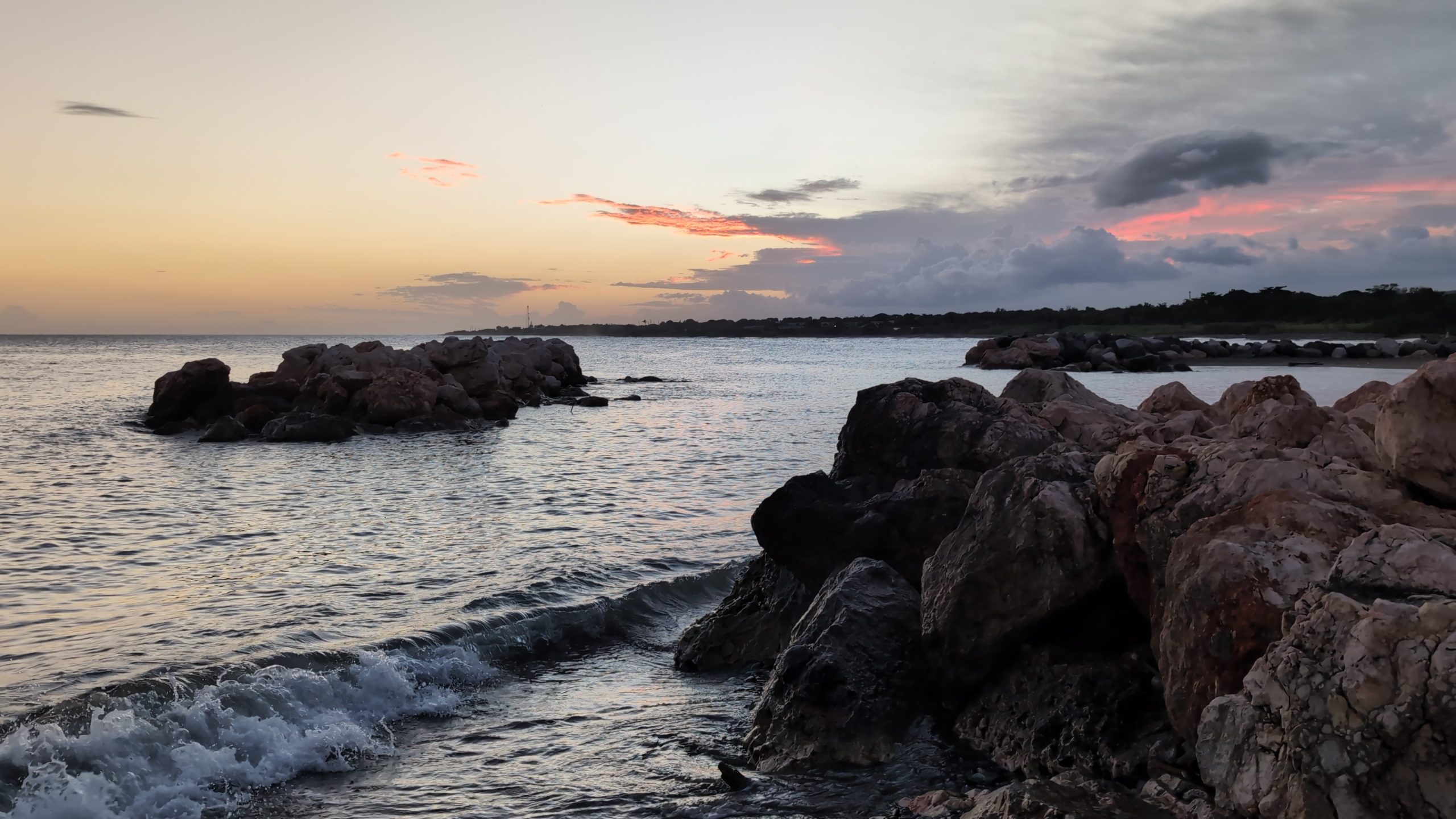 Golden sunset over Baileys Beach in St. Thomas, Jamaica with calm Caribbean waters.
